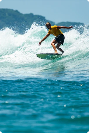 Surfer riding a wave on a sunny day, showcasing the excitement of surf lessons at Sagres Sun Stay