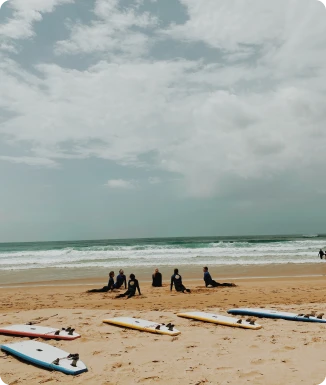 Beginner surfers practicing techniques on the beach before heading into the water during their surf lessons